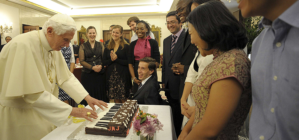 Parishioner Claire Brown (second left) is seen as Pope Benedict XVI pretends to play a piano made out of cake after meeting  young people for lunch during the 2011 World Youth Day in Madrid, Spain. Image: Supplied